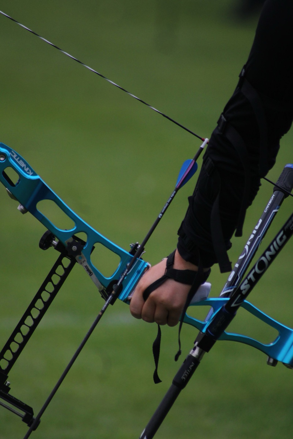 Close-up of the archer's hand on the bow, arrow nocked on the string