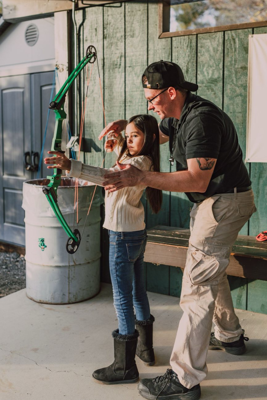 Young archer guided by the instructor