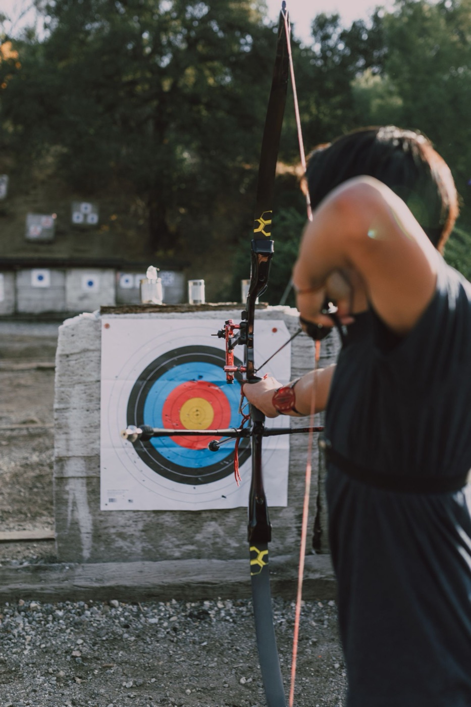 Archer seen from behind aiming at the target in evening light