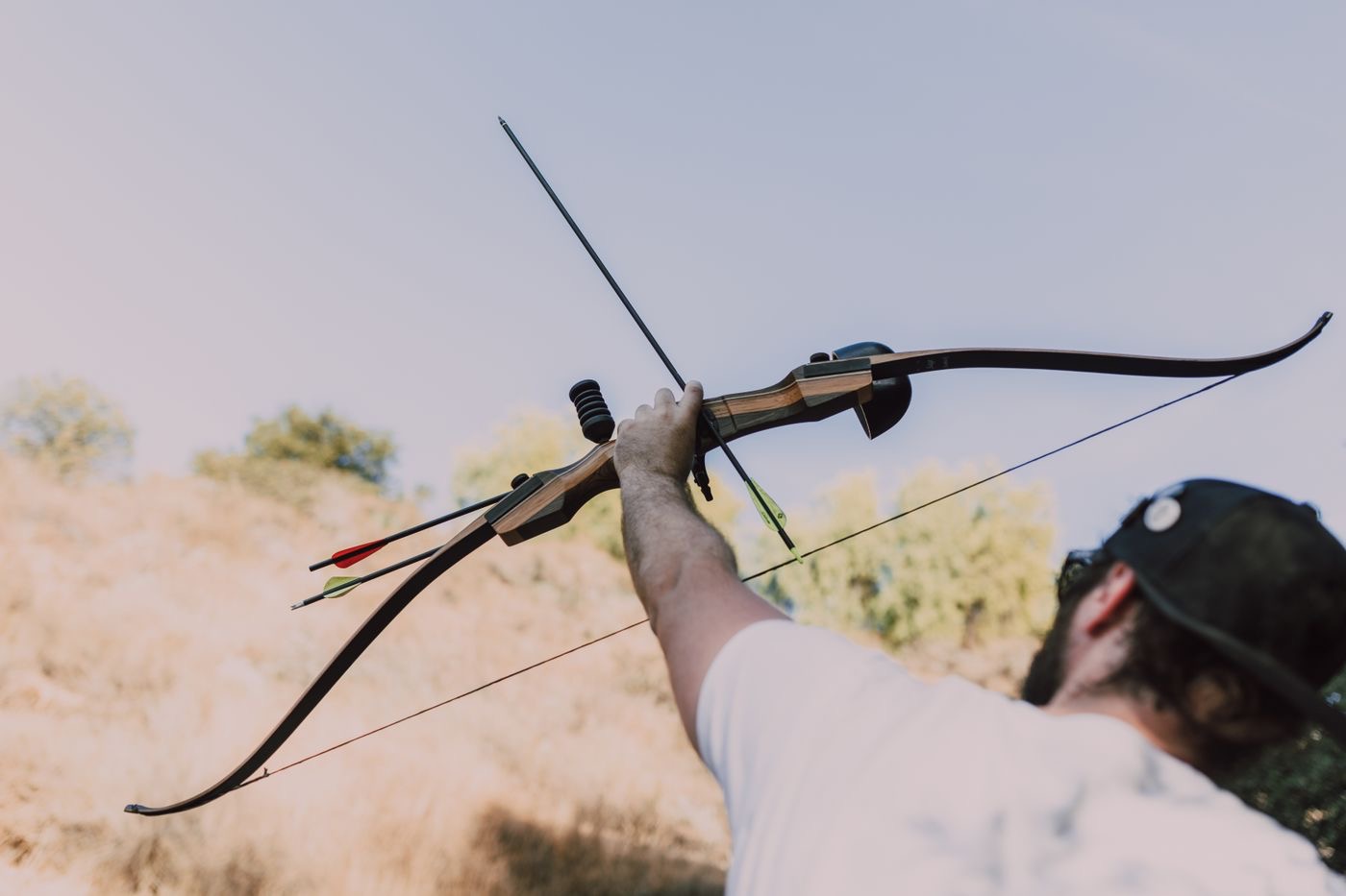 Archer aiming a recurve bow outdoors